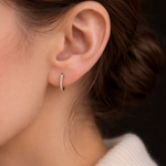 A woman wearing the Modernist Graduating Pave Hoop, a small gold earring with sparkling pave stones.