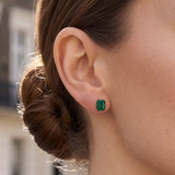 Close-up of a woman wearing a rectangular London Bridge Emerald Stud earring, with her brown hair pulled back in a bun.